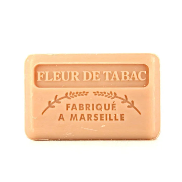 A rectangular peach-colored bar of soap with embossed text reading 'FLEUR DE TABAC' and 'FABRIQUÉ A MARSEILLE' on a plain white background.