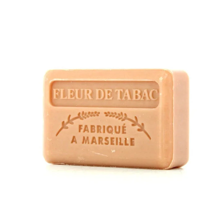 A rectangular bar of peach-colored soap embossed with 'FLEUR DE TABAC' and 'FABRIQUÉ A MARSEILLE' on a clean white background.